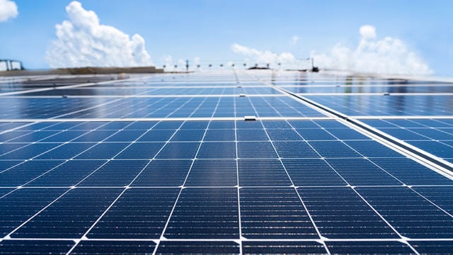 Solar panels are installed on a rooftop under a clear blue sky.